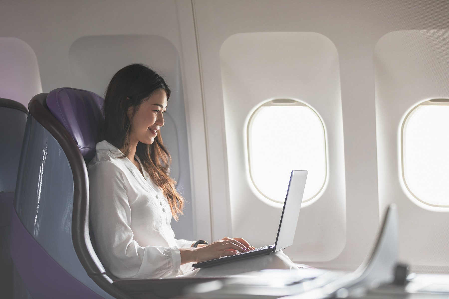 Why Every CEO Needs To Join A Benefits Program Like Exec - Woman Working On Laptop On Plane